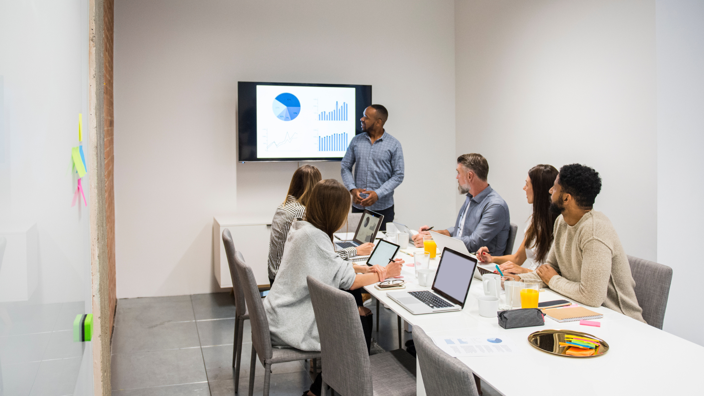 A group of professionals gathered around a table with laptops, discussing strategies for IT downtime prevention.