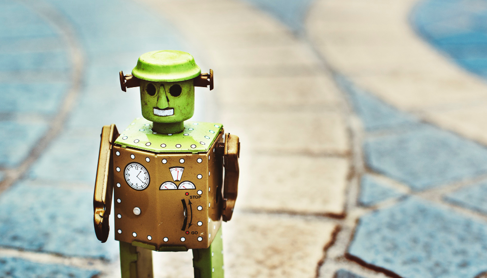 A green robot stands on a blue tile floor, symbolizing the need for website redesign due to outdated technology.