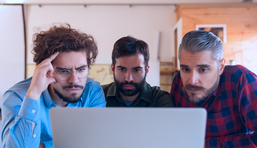 Three men collaborating over a laptop, discussing strategies on how to beat web competition effectively.